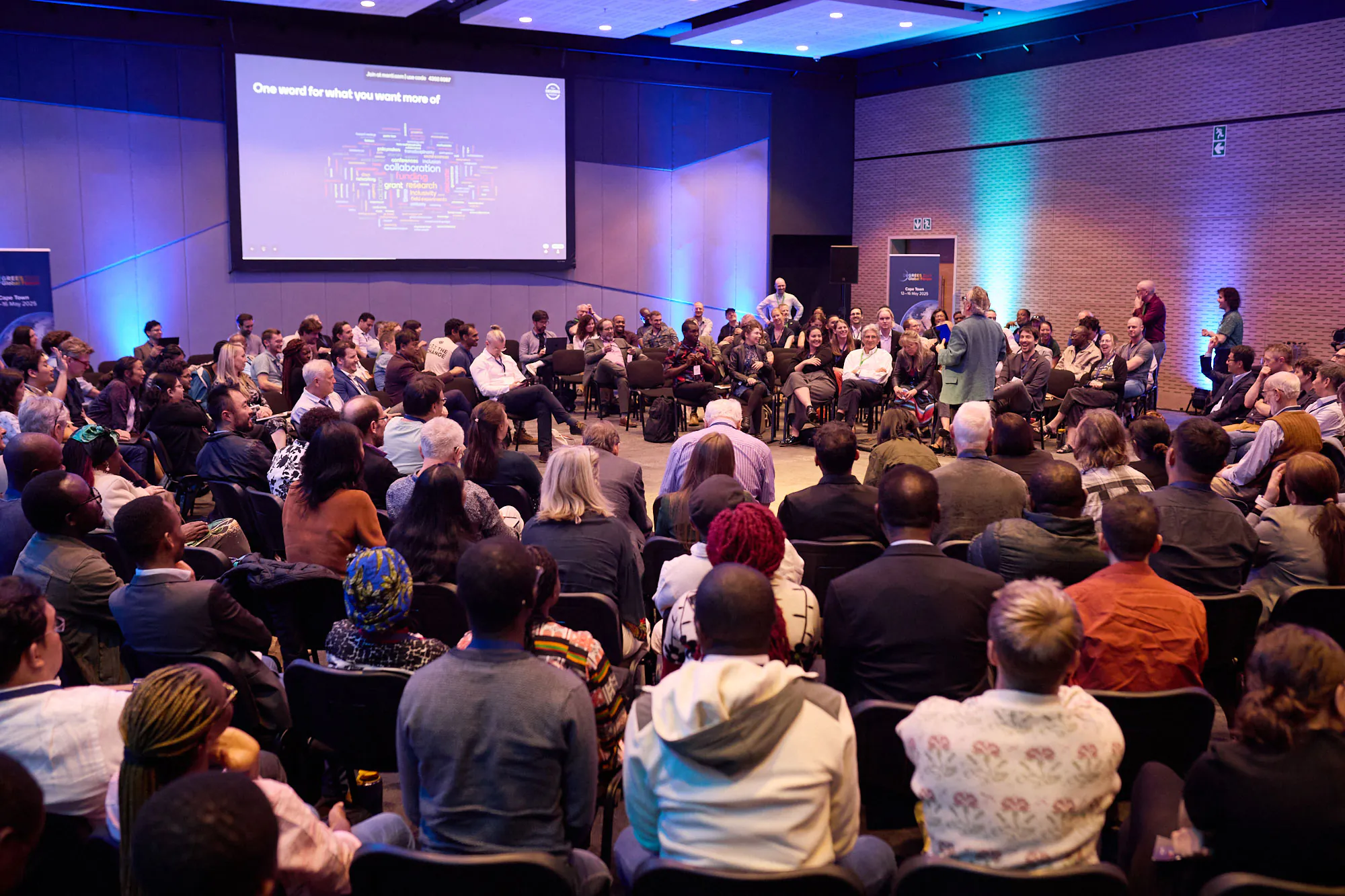 dozens of people seated in concentric circles around a central speaker